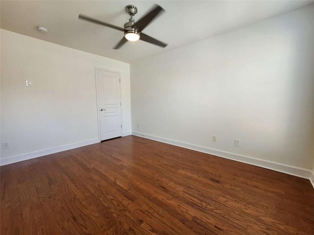 spare room featuring dark wood-style floors, ceiling fan, and baseboards