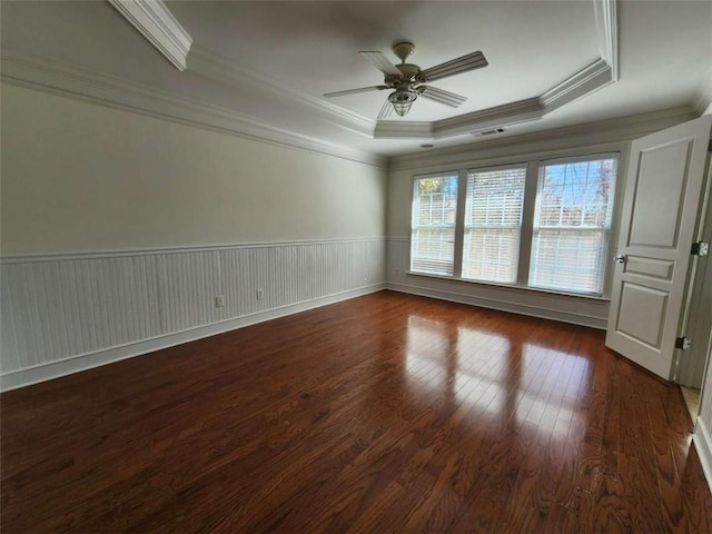 unfurnished room with a raised ceiling, wainscoting, ceiling fan, hardwood / wood-style floors, and crown molding