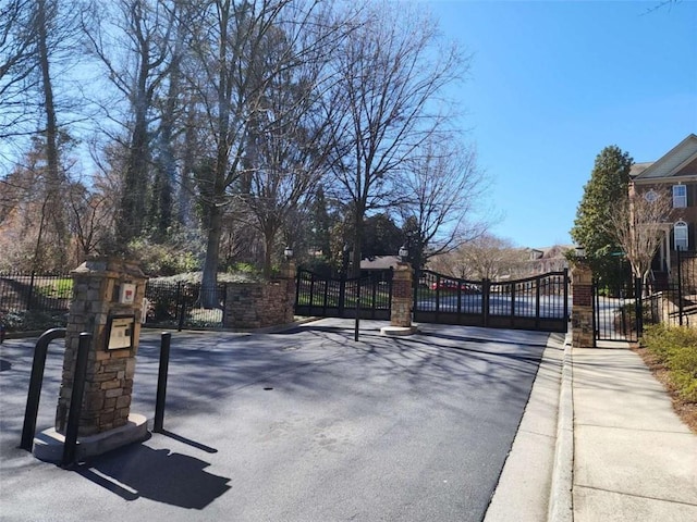 view of road with a gate, sidewalks, curbs, and a gated entry