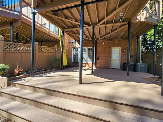 view of patio with a deck, central AC unit, and fence