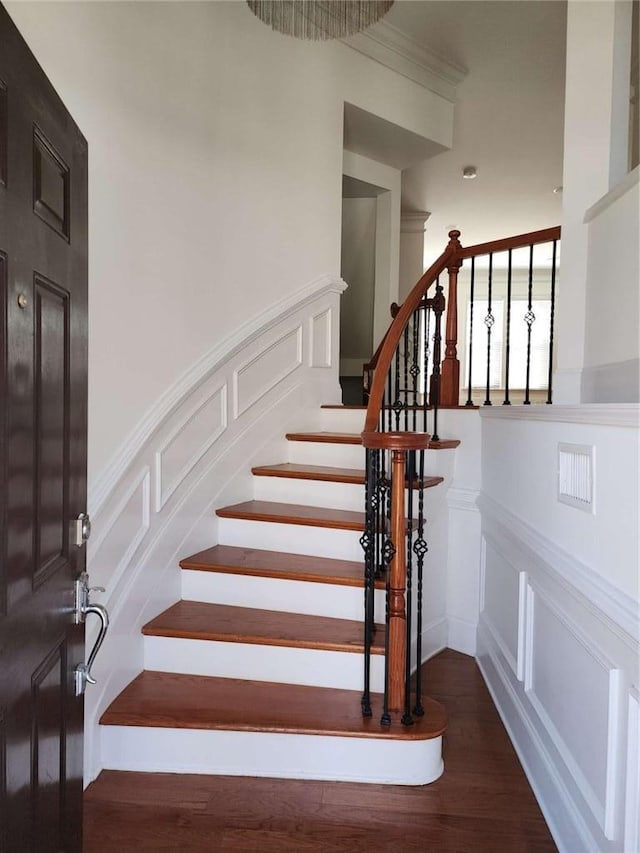 stairway with wood finished floors and a decorative wall