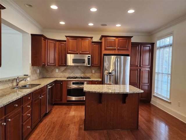 kitchen featuring appliances with stainless steel finishes, dark wood-style flooring, a sink, and light stone counters