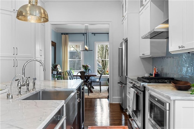 kitchen featuring white cabinets, decorative backsplash, premium appliances, wall chimney exhaust hood, and dark wood-style flooring