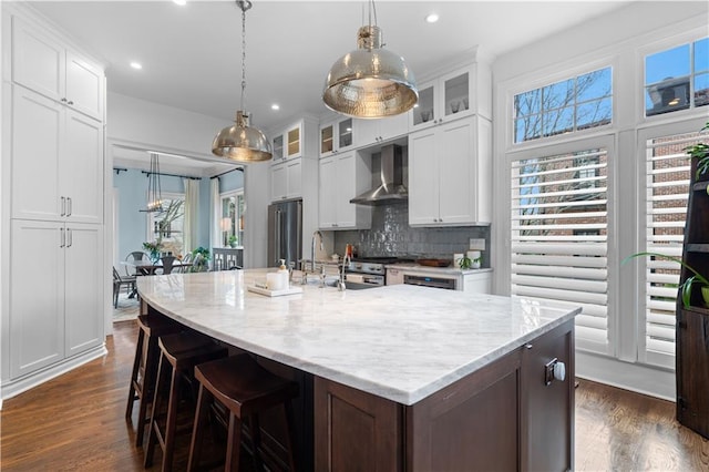 kitchen featuring a sink, wall chimney exhaust hood, dark wood-style flooring, and premium appliances