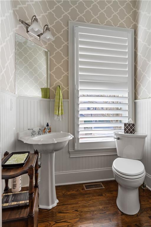 bathroom featuring toilet, wood finished floors, visible vents, and wallpapered walls