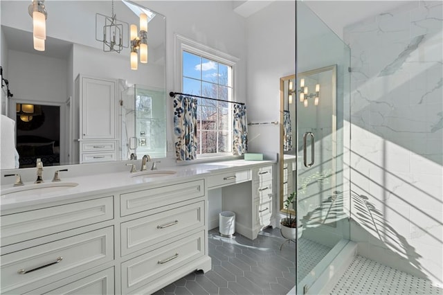 full bathroom with double vanity, a stall shower, a sink, and an inviting chandelier