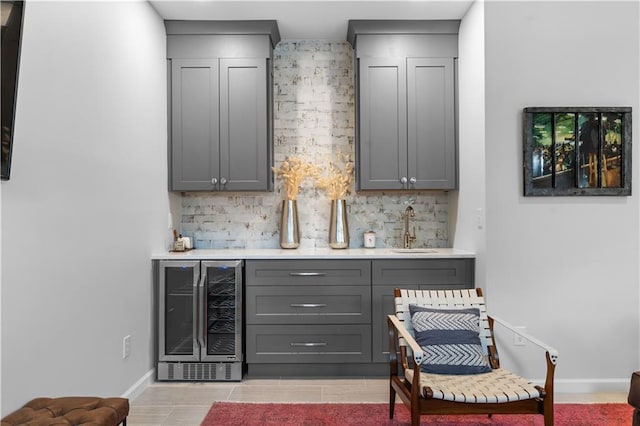 bar with tasteful backsplash, beverage cooler, indoor wet bar, and a sink