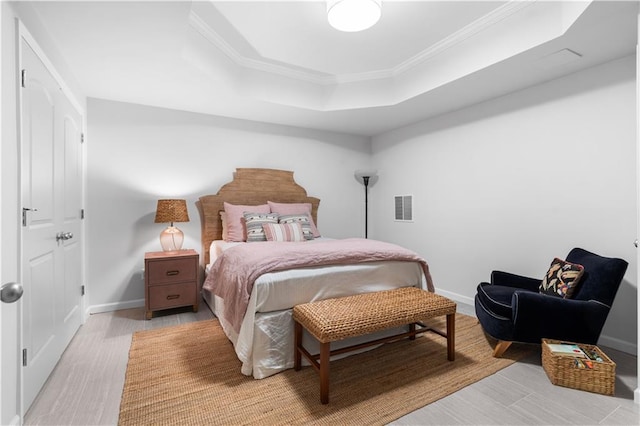 bedroom featuring baseboards, a tray ceiling, visible vents, and crown molding