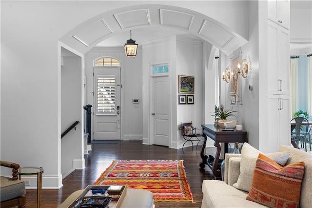 entryway with arched walkways, dark wood-style floors, and baseboards