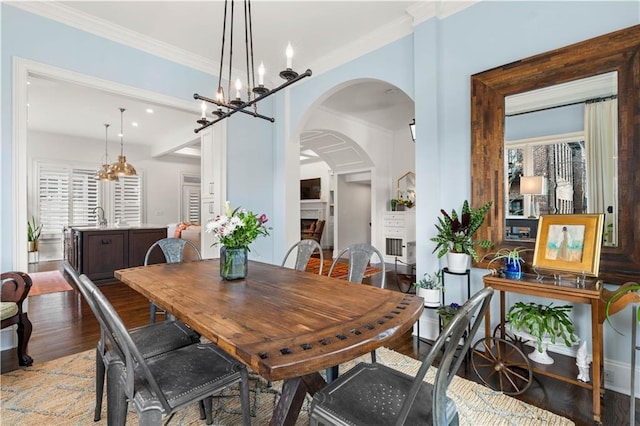 dining space featuring a lit fireplace, crown molding, and wood finished floors