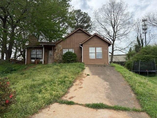 4817 Mainstreet Valley Trce, Stone Mountain, GA 30088 - view of front of property featuring a trampoline, driveway, a chimney, and stone siding