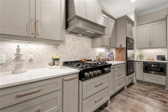 131 Forsyth Park Ln, Woodstock, GA 30188 - kitchen with wall chimney exhaust hood, black gas cooktop, gray cabinetry, double wall oven, and backsplash