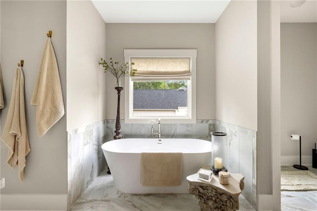 131 Forsyth Park Ln, Woodstock, GA 30188 - bathroom featuring marble finish floors, a freestanding tub, tile walls, and a wainscoted wall