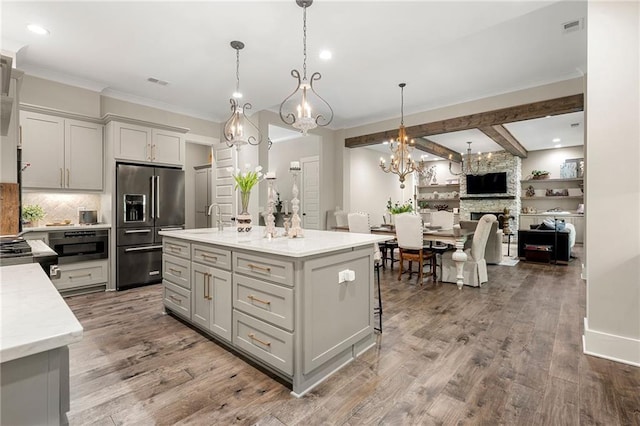 131 Forsyth Park Ln, Woodstock, GA 30188 - kitchen featuring high end fridge, a chandelier, tasteful backsplash, crown molding, and an island with sink