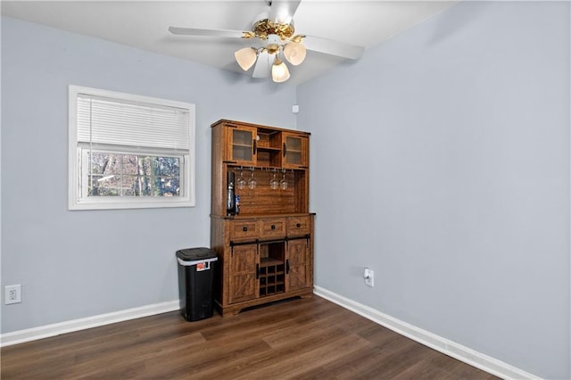 empty room featuring dark wood finished floors, baseboards, and ceiling fan