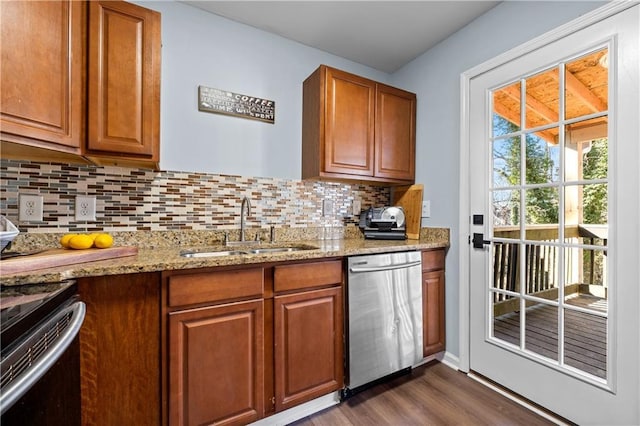 kitchen featuring tasteful backsplash, dark wood finished floors, light stone counters, stainless steel dishwasher, and a sink