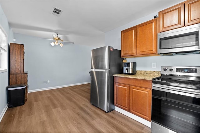 kitchen featuring visible vents, appliances with stainless steel finishes, brown cabinets, and wood finished floors