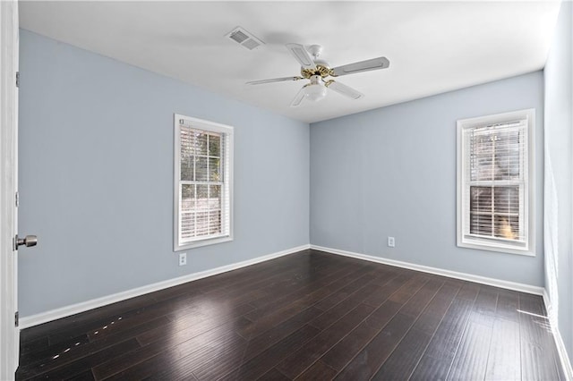 unfurnished room with dark wood-style floors, visible vents, ceiling fan, and baseboards