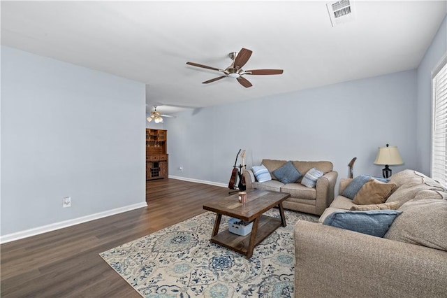 living room featuring ceiling fan, wood finished floors, visible vents, baseboards, and a glass covered fireplace