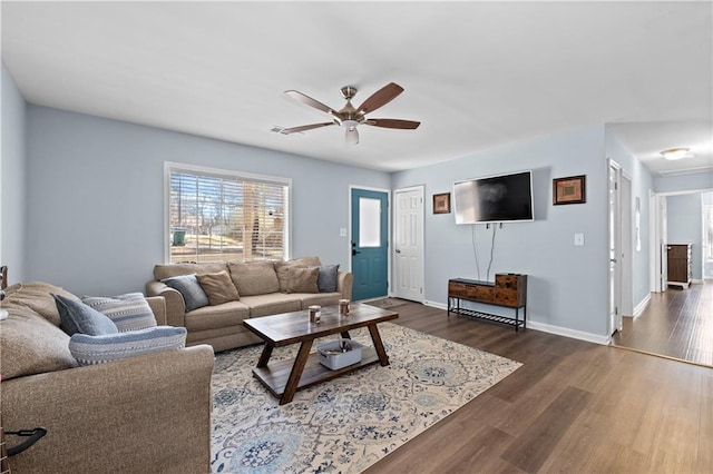 living room with dark wood-type flooring, ceiling fan, and baseboards