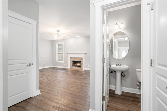 bathroom featuring ceiling fan, a high end fireplace, wood-type flooring, and toilet