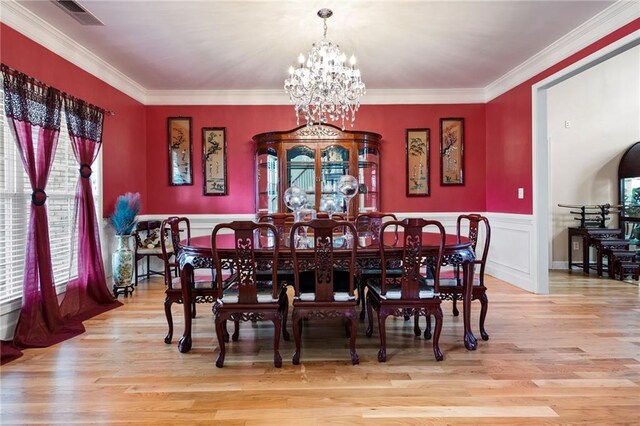 dining space featuring a chandelier, light wood-type flooring, a wainscoted wall, and visible vents