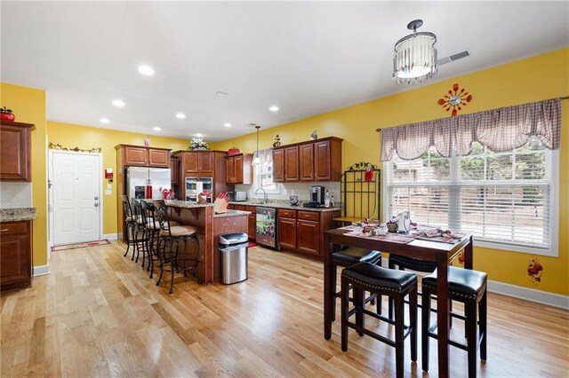 kitchen with a kitchen island, a kitchen breakfast bar, decorative light fixtures, stainless steel appliances, and a sink