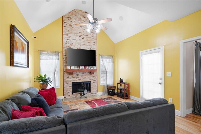 living room featuring a fireplace, light wood finished floors, ceiling fan, high vaulted ceiling, and baseboards