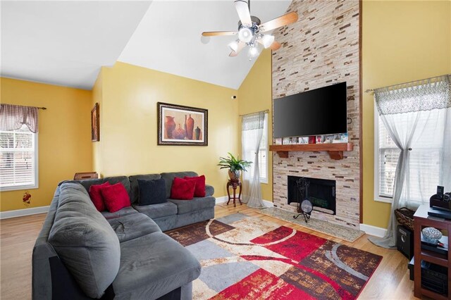 living room with high vaulted ceiling, a fireplace, baseboards, and wood finished floors