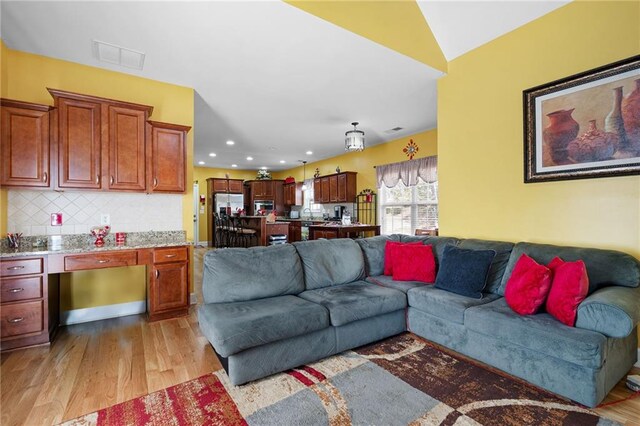 living area with recessed lighting, visible vents, and light wood finished floors