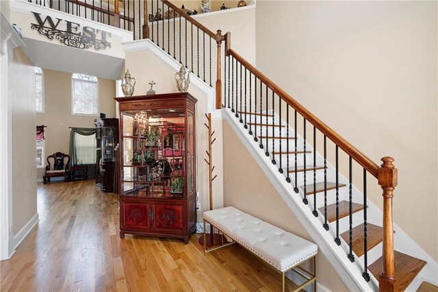 staircase with a towering ceiling, baseboards, and wood finished floors