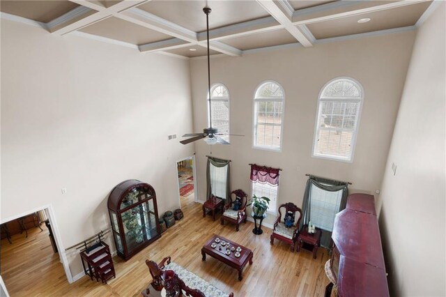 interior space featuring ceiling fan, coffered ceiling, baseboards, light wood finished floors, and beamed ceiling