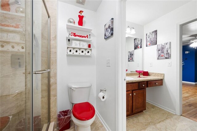 bathroom with a stall shower, baseboards, vanity, and toilet