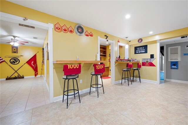 kitchen featuring light tile patterned floors, a kitchen bar, baseboards, and recessed lighting