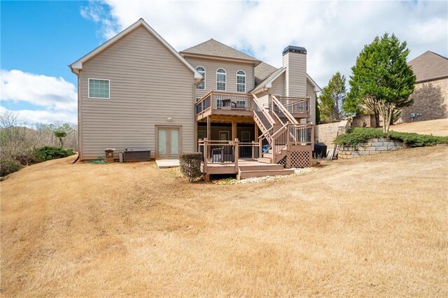 rear view of property featuring a lawn, a chimney, stairs, a wooden deck, and central air condition unit