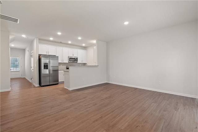 kitchen featuring kitchen peninsula, white cabinets, stainless steel appliances, and light wood-type flooring