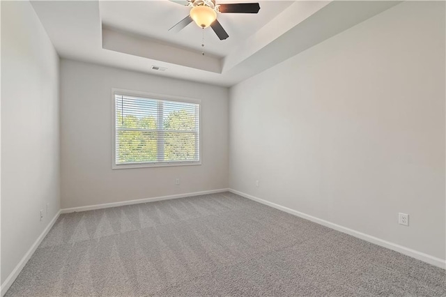 carpeted empty room featuring a tray ceiling and ceiling fan