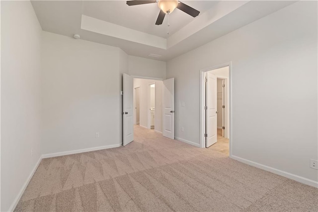 carpeted empty room with a tray ceiling and ceiling fan