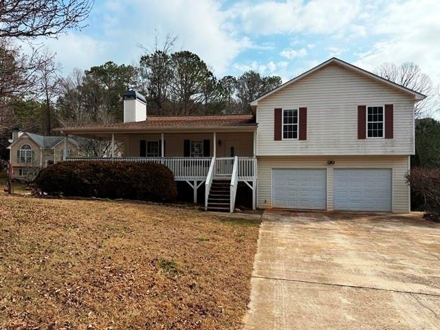 view of front of property with a garage, covered porch, and a front lawn