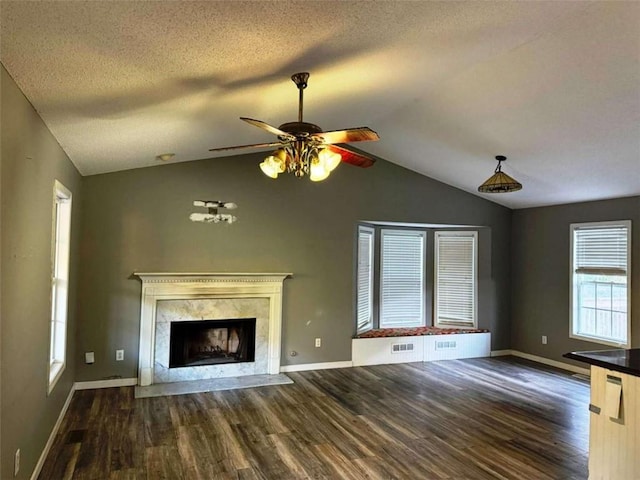 unfurnished living room with lofted ceiling, a fireplace, dark hardwood / wood-style floors, and a textured ceiling