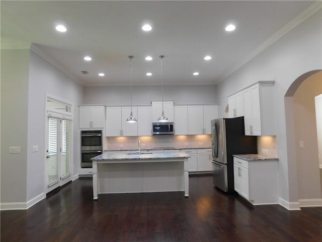 330 La Perla Dr, Sugar Hill, GA 30518 - kitchen featuring appliances with stainless steel finishes, arched walkways, crown molding, tasteful backsplash, and light stone countertops