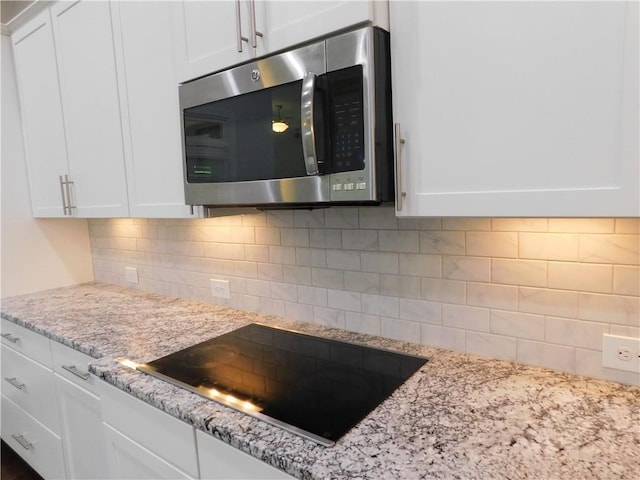 330 La Perla Dr, Sugar Hill, GA 30518 - kitchen view of stainless steel microwave, black electric cooktop, and white cabinets