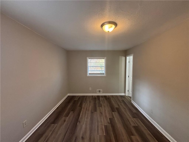 unfurnished room featuring a textured ceiling and dark hardwood / wood-style flooring