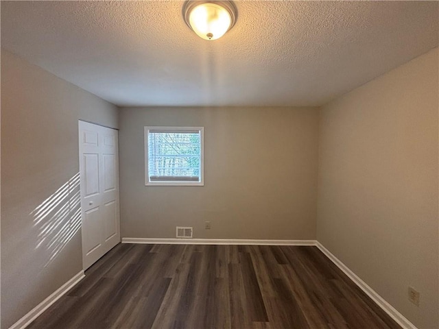 spare room featuring dark hardwood / wood-style floors and a textured ceiling