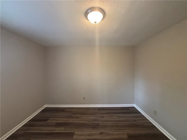 spare room featuring dark wood-type flooring and a textured ceiling