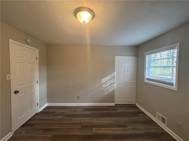 empty room with dark hardwood / wood-style floors and a textured ceiling