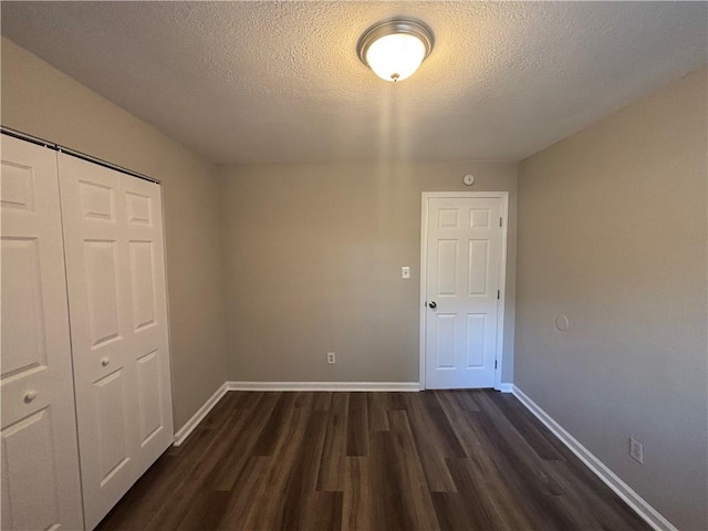 unfurnished bedroom featuring dark hardwood / wood-style floors, a closet, and a textured ceiling