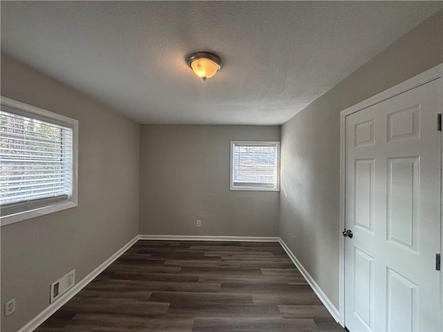 empty room with dark hardwood / wood-style floors and a textured ceiling