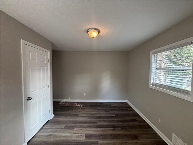 unfurnished room with dark wood-type flooring