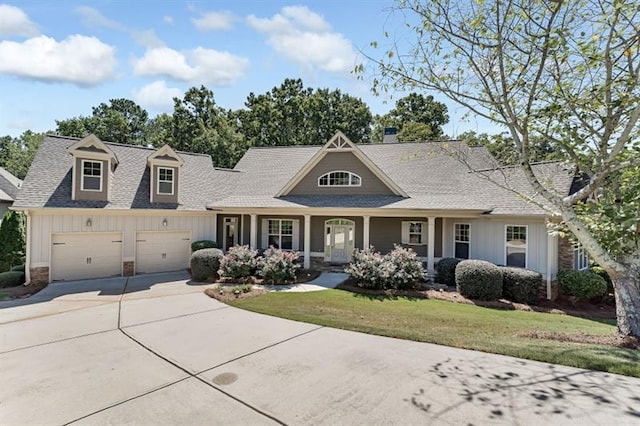 view of front of home featuring a front yard, a garage, and covered porch